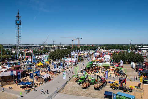 Aerial view of the open-air grounds of Messe München during INTERFORST. People bustle between colourful exhibition stands and forestry machinery.
