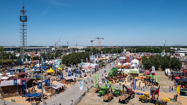 Aerial view of the open-air grounds of Messe München during INTERFORST. People bustle between colourful exhibition stands and forestry machinery.