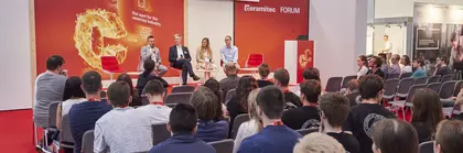 Vier Personen sitzen bei einer Podiumsdiskussion vor Publikum auf der Bühne des ceramitec Forum.