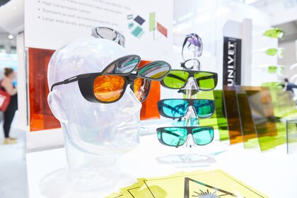 An exhibition stand with various safety glasses with colored lenses. One of them on a mannequin head.