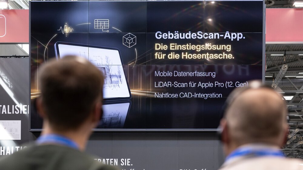 Menschen mit Kopfhörern nehmen an einer geführten Tour teil und Blicken auf einen Screen, der eine Gebäude-Scan-App erläutert.