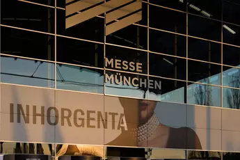 Reflection of a building on the glass façade of the Munich Trade Fair Centre with an INHORGENTA advertisement.