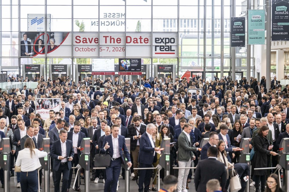 A large crowd enters a convention center for Expo Real, with a banner displaying the event dates in October 2026.