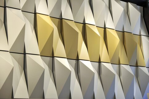Geometric wall panels with angular white and gold 3D shapes create a modern, textured pattern.