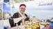 Traditionally dressed man at a Tunisia stand at a travel fair, artfully working sheet metal.