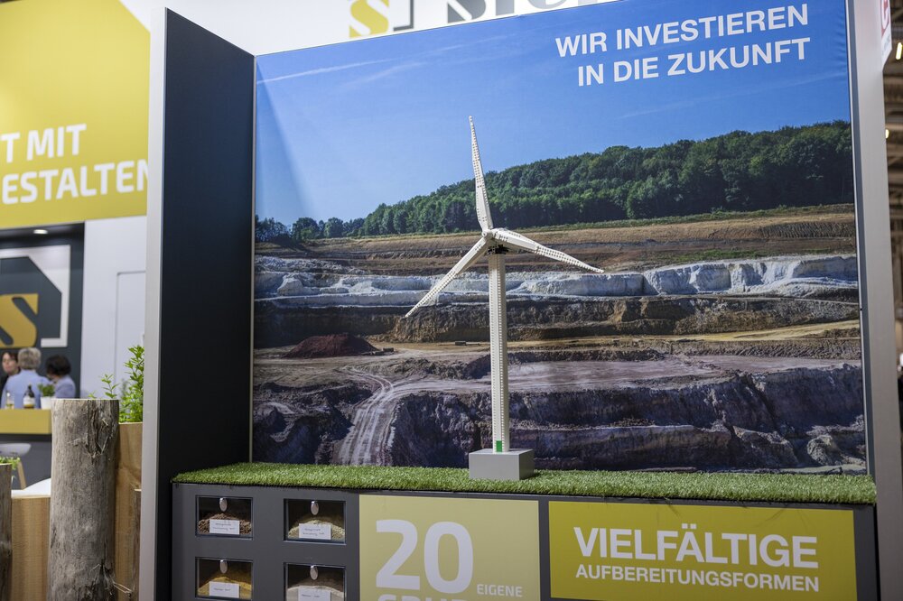 Wind turbine model in front of a landscape backdrop in an exhibition with German text on the subject of 