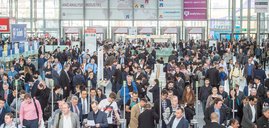 Entrance to the analytica trade fair with many people passing through the turnstiles.