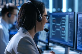 Frau und Mann mit Headsets im Gespräch vor Computern