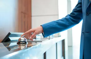 Symbolic image - a person presses a bell at a hotel reception with one finger.