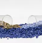 Two horizontal, open test tubes with blue and gold grains against a white background.