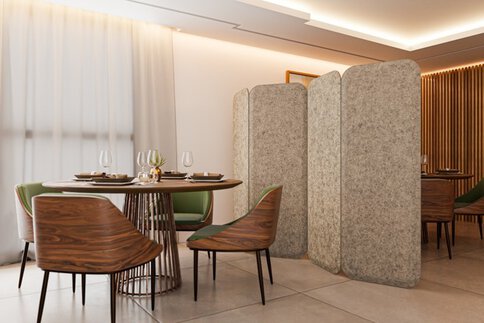 Modernes Restaurantinterieur mit runden Holztischen, Designstühlen und freistehenden Akustik-Trennwänden zur Raumgliederung, die gleichzeitig ein Heizungspaneel sind.