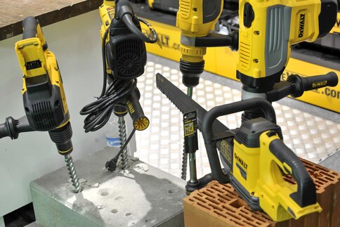 Several yellow DeWalt drills and tools were used to drill holes in concrete and brick blocks.