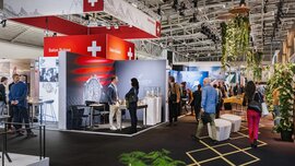 A view of a crowded exhibition hall during INHORGENTA, featuring numerous booths, promotional banners, and plant decorations.