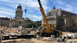 Baustelle auf dem Berliner Gendarmenmarkt mit einem Kran, der Wasserleitungen verlegt 