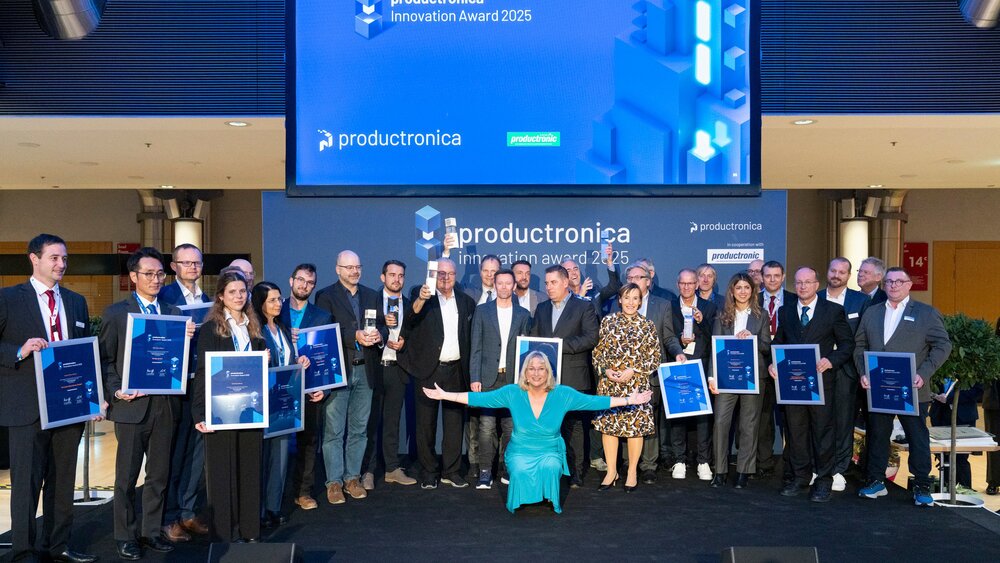 Ein Gruppenbild aller Gewinner des productronica Innovation Awards 2025, die mit ihren Auszeichnungen auf der Bühne stehen und lächeln.