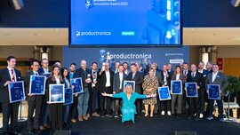 Ein Gruppenbild aller Gewinner des productronica Innovation Awards 2025, die mit ihren Auszeichnungen auf der Bühne stehen und lächeln.