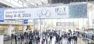 Menschenmenge in der Messeeingangshalle. Im Fokus ist ein von der Decke hängendes Schild mit der Aufschrift 