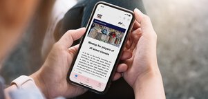 Person holding a smartphone, on which the EXPO REAL visitor information is displayed, with the theme 