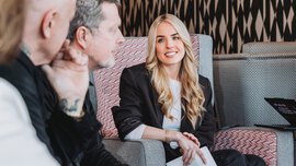Two women and two men are sitting together on upholstered furniture in a colorfully decorated corner, looking at each other.