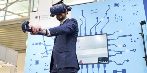 Person in a suit using a virtual reality headset and controller in a technologically designed room.