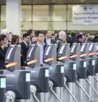 A large crowd waits behind the machines for admission control before the trade fair begins.