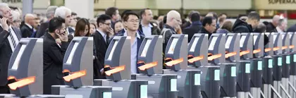 A large crowd waits behind the machines for admission control before the trade fair begins.