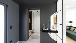 Ein moderner grauer Flur in kantigem Design mit Blick auf die Haustür. Rechts geht es in den Wohnbereich.