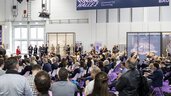 Ein Publikum aus sitzenden und stehenden Menschen während einer Präsentation im Forum Halle 1 auf der digitalBAU.