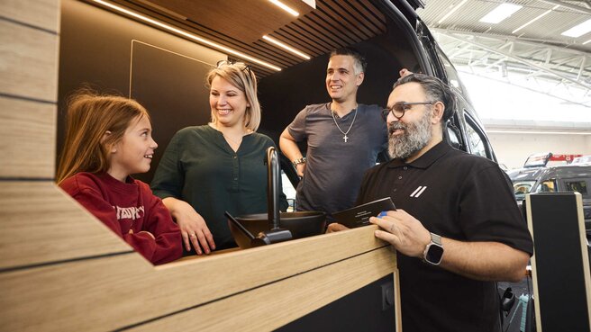Eine Familie besichtigt einen Campervan auf der Messe f.re.e und unterhält sich mit einem Aussteller über die Innenausstattung.