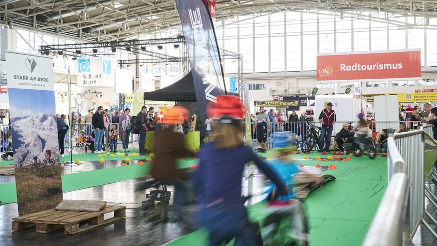 Mehrere Kinder testen Fahrräder auf der Fahrrad Parcours Fläche auf der free Messe