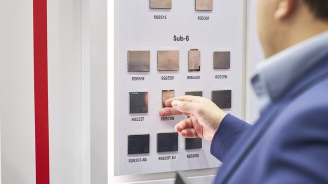 Various Sub-6 radio modules are displayed on a panel on the wall. A man in a suit looks at the modules and touches one of them with his hand.
