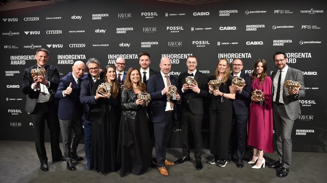 The winners of the INHORGENTA AWARD 2025 present their trophies in front of a logo wall at the gala.