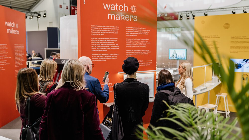 A group of people viewing a watch manufacturer's exhibition in a modern showroom.