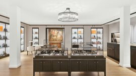 A large salesroom with two columns, a round chandelier, and numerous square display cases in which jewelry is presented.