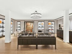 A large salesroom with two columns, a round chandelier, and numerous square display cases in which jewelry is presented.