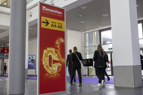 Mehrere Personen gehen durch die Gänge der Messe, neben einem ceramitec Wegweiser für die Hallen A4-A6.