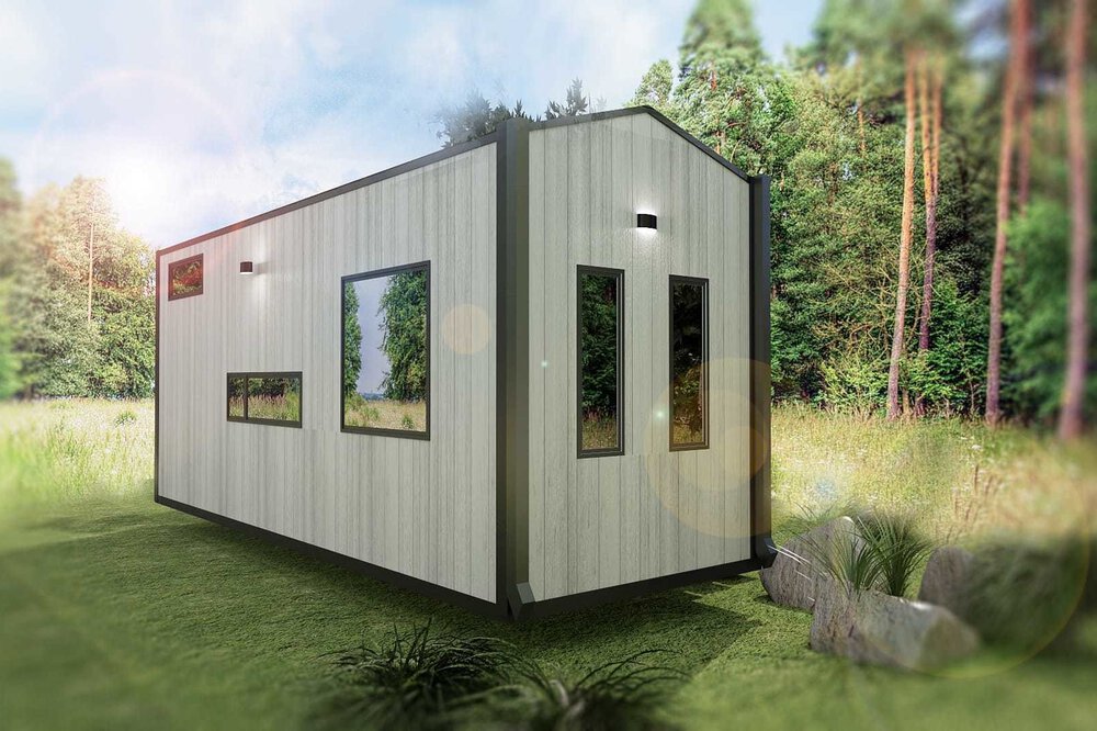 Modernes Tiny House mit großen Fenstern in einer Rasenfläche, umgeben von Bäumen.