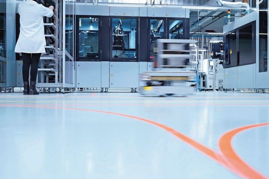 Laboratory with a person in a lab coat and machines in the background and a Robotoer driving past.