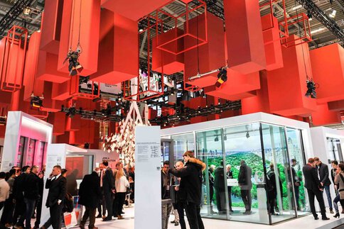 Blick auf einen Messestand der BAU mit Fokus auf die Hallendecke, an der zahlreiche rote Quader und Quaderrahmen in verschiedenen größen hängen.