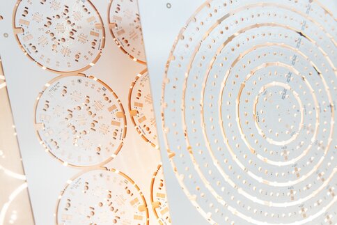 Close-up of complex milled, round circuit boards with screw holes.