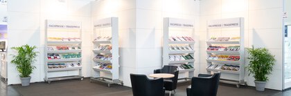 Stand with chairs, table and shelves displaying trade press brochures.