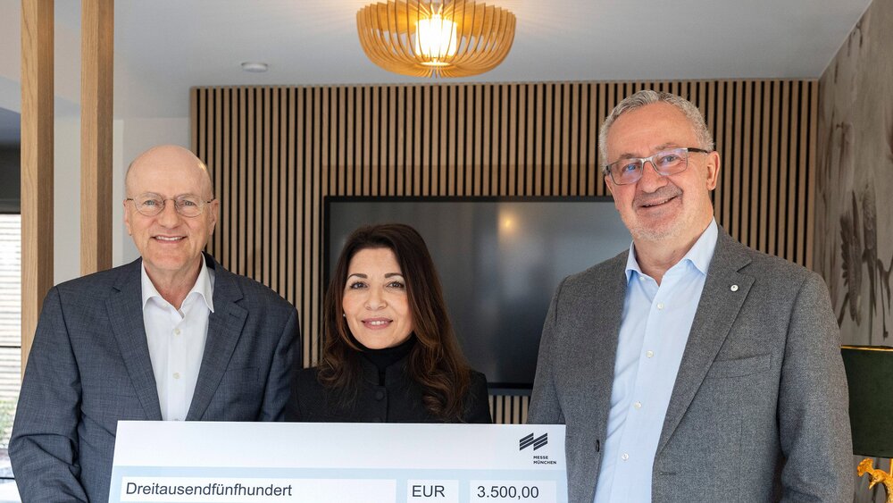 Drei lächelnde Menschen, die einen großen Spendenscheck über 3.500 Euro für einen inklusiven Spielplatz in der Hand halten.