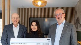 Drei lächelnde Menschen, die einen großen Spendenscheck über 3.500 Euro für einen inklusiven Spielplatz in der Hand halten.