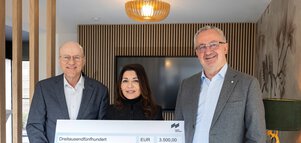 Drei lächelnde Menschen, die einen großen Spendenscheck über 3.500 Euro für einen inklusiven Spielplatz in der Hand halten.