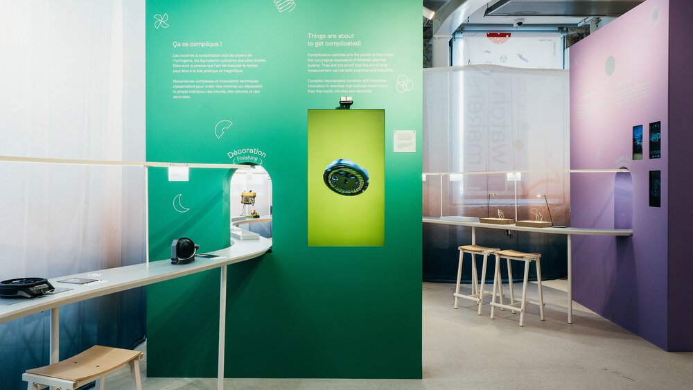 An exhibition stand at INHORGENTA with a long winding table with workstations and several large colourful information walls.