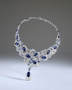 Close-up of a delicate silver necklace with numerous dark blue teardrop-shaped gemstones set into it.