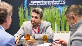 Three trade fair visitors are having a conversation at a table.