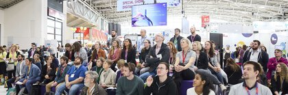 At analytica, many people sit and stand in a hall and follow a special show