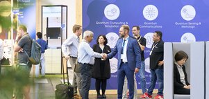 People are chatting in front of a large blue wall with the slogan “Our mission is empowering Europe's quantum future.”