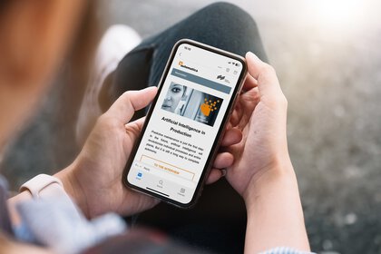 Person holding a smartphone displaying an automatica newsletter entitled 